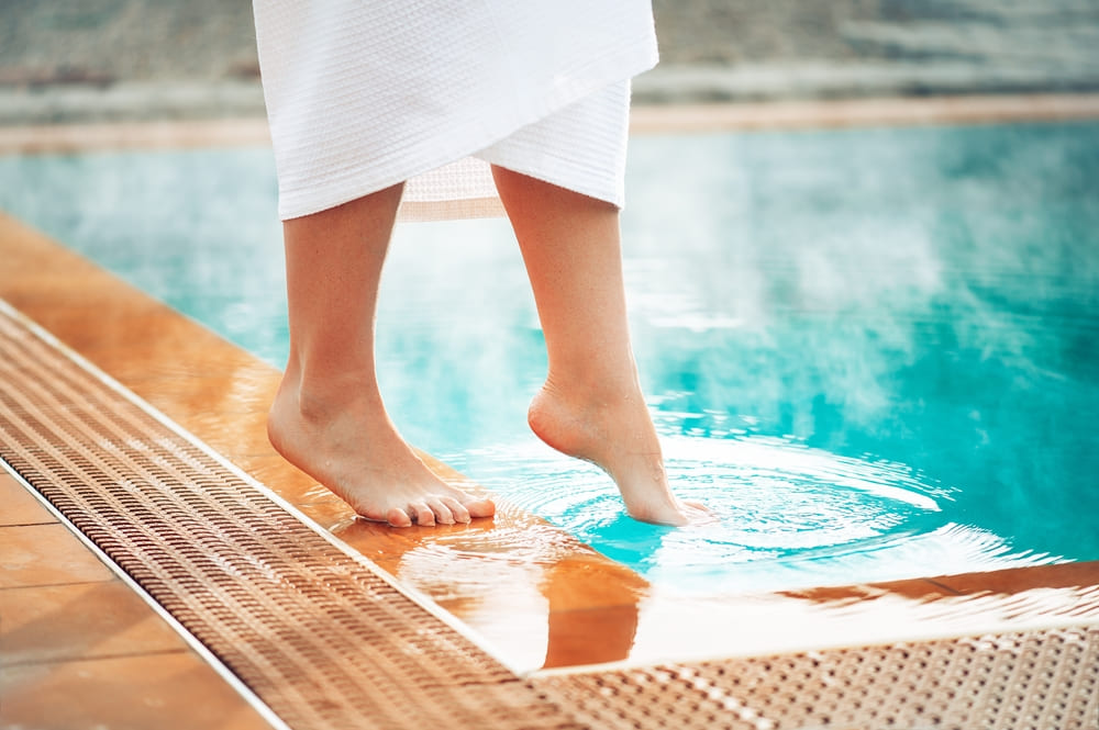 person dipping toe into pool during winter